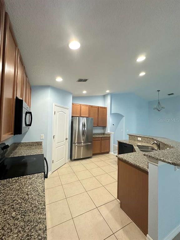 A kitchen features light blue walls, wood cabinets, granite countertops, and stainless steel appliances — 10816 CABBAGE TREE LOOP, ORLANDO, FL