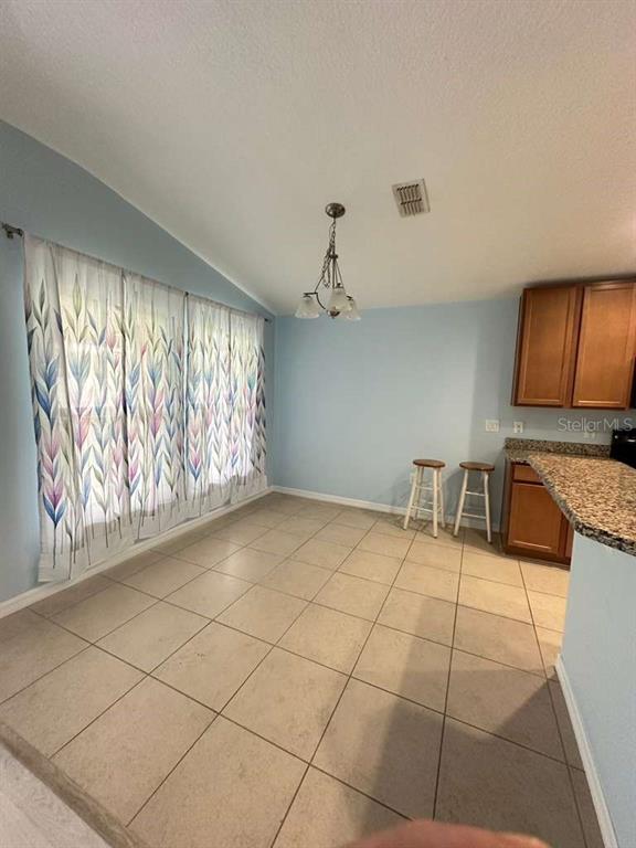 A dining area features light blue walls, tile flooring, a chandelier, and a breakfast bar — 10816 CABBAGE TREE LOOP, ORLANDO, FL