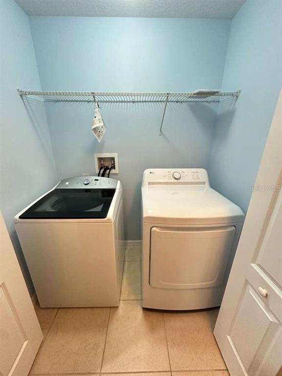 A laundry room features a top-loading washer, a dryer, and a wire shelf on light-blue walls — 10816 CABBAGE TREE LOOP, ORLANDO, FL