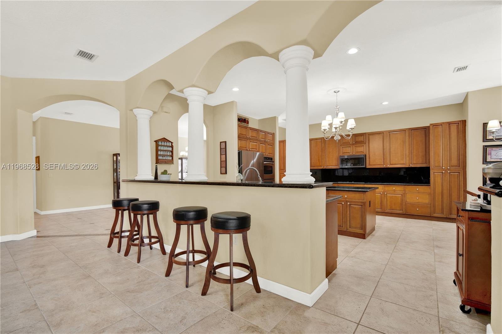 A kitchen features wood cabinetry, black granite countertops, stainless steel appliances, and a chandelier — 7823 SW 195th Ter, Cutler Bay FL 33157, CUTLER BAY, FL