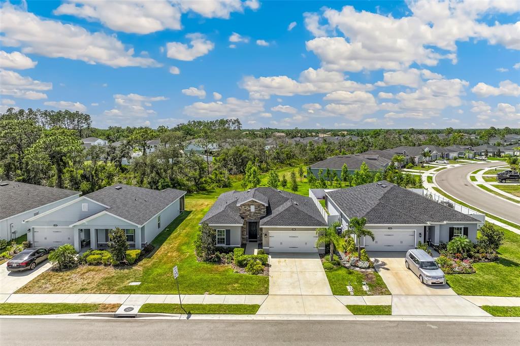 An aerial view shows three suburban houses with driveways and lawns along a paved street — 17131 11TH TERRACE E, BRADENTON, FL