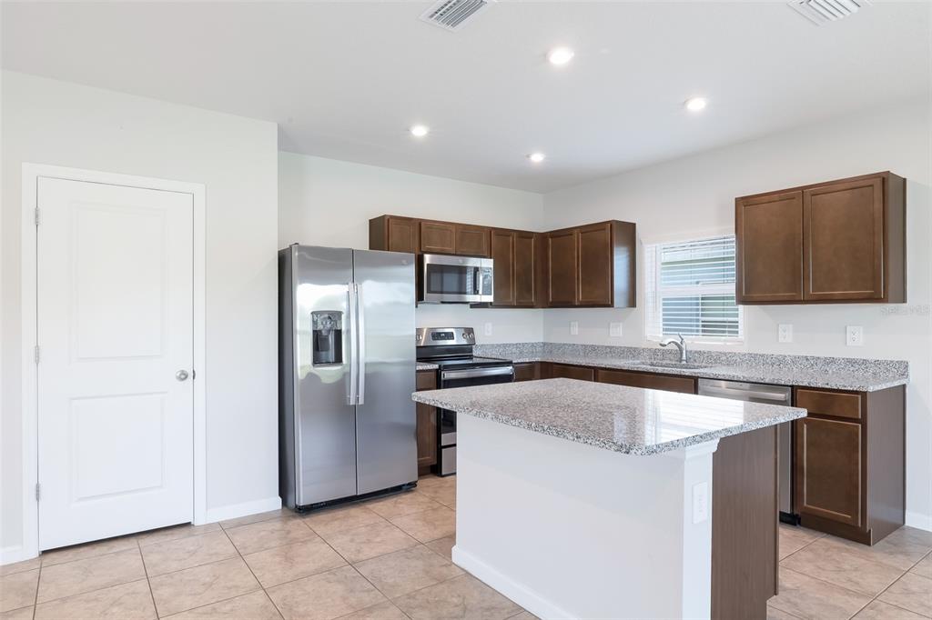 A kitchen features dark wood cabinets, granite countertops, stainless steel appliances, and a center island — 17131 11TH TERRACE E, BRADENTON, FL