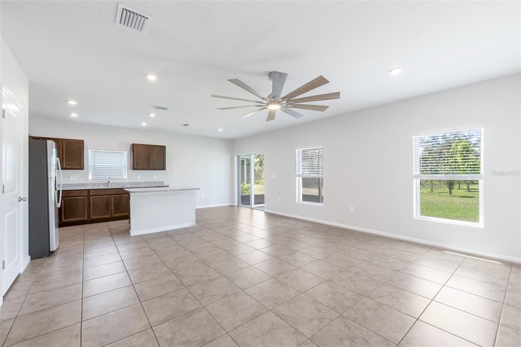 A bright, open-concept kitchen and living area features tile flooring, dark cabinetry, and a ceiling fan — 17131 11TH TERRACE E, BRADENTON, FL