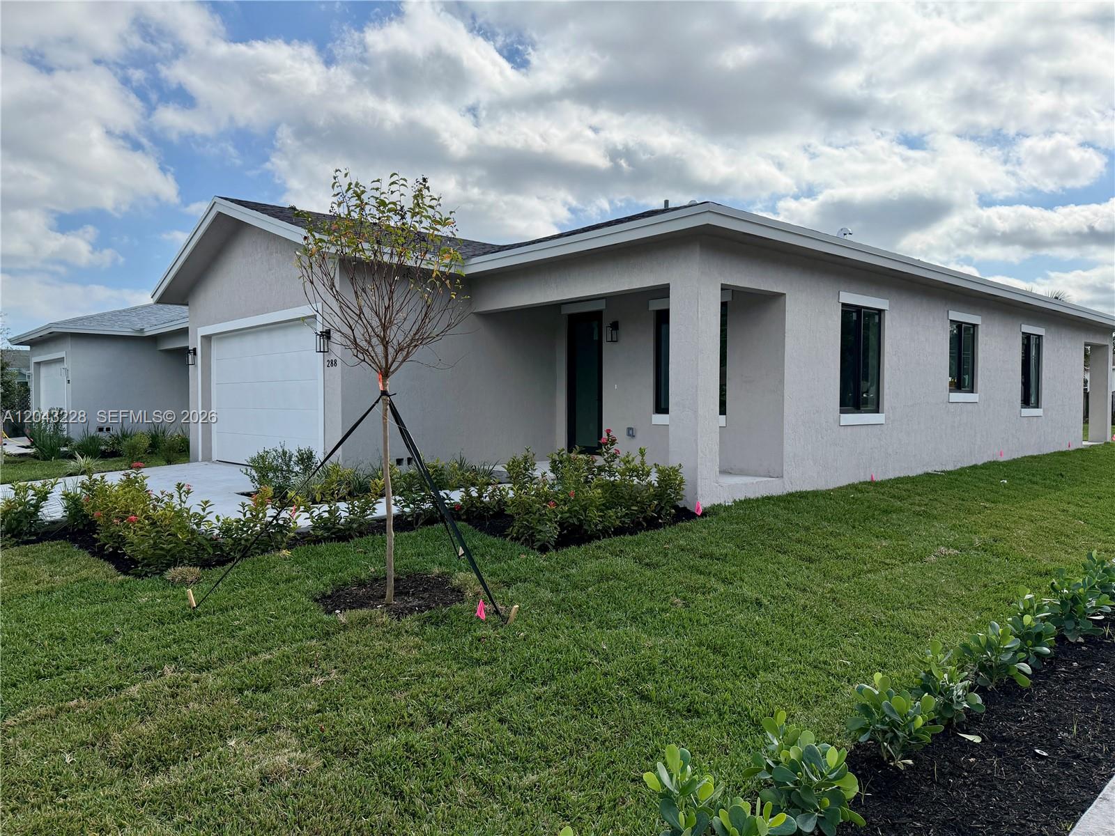 A single-story house with a white garage, gray stucco exterior, and a landscaped front yard — 288 SW 2nd Ct, Deerfield Beach FL 33441, DEERFIELD BEACH, FL