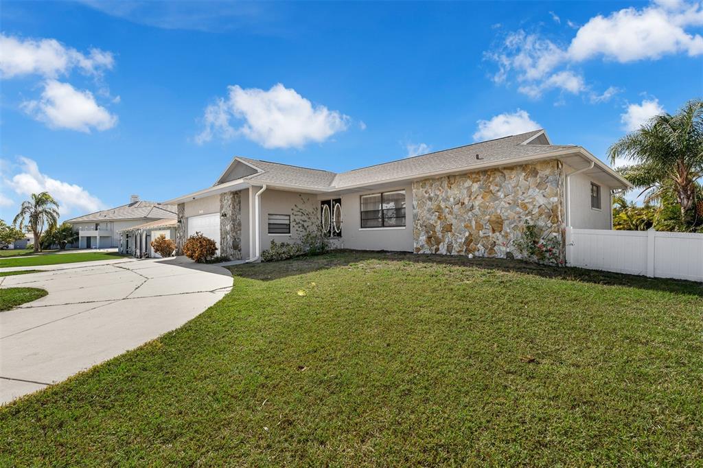 A single-story house with a stone facade, gray roof, and a concrete driveway — 3848 TOPSAIL TRAIL, NEW PORT RICHEY, FL