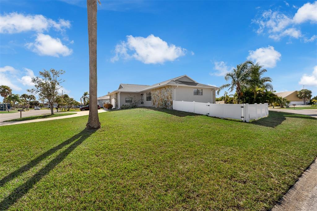 A single-story house with stone siding and a white vinyl fence sits on a lawn — 3848 TOPSAIL TRAIL, NEW PORT RICHEY, FL