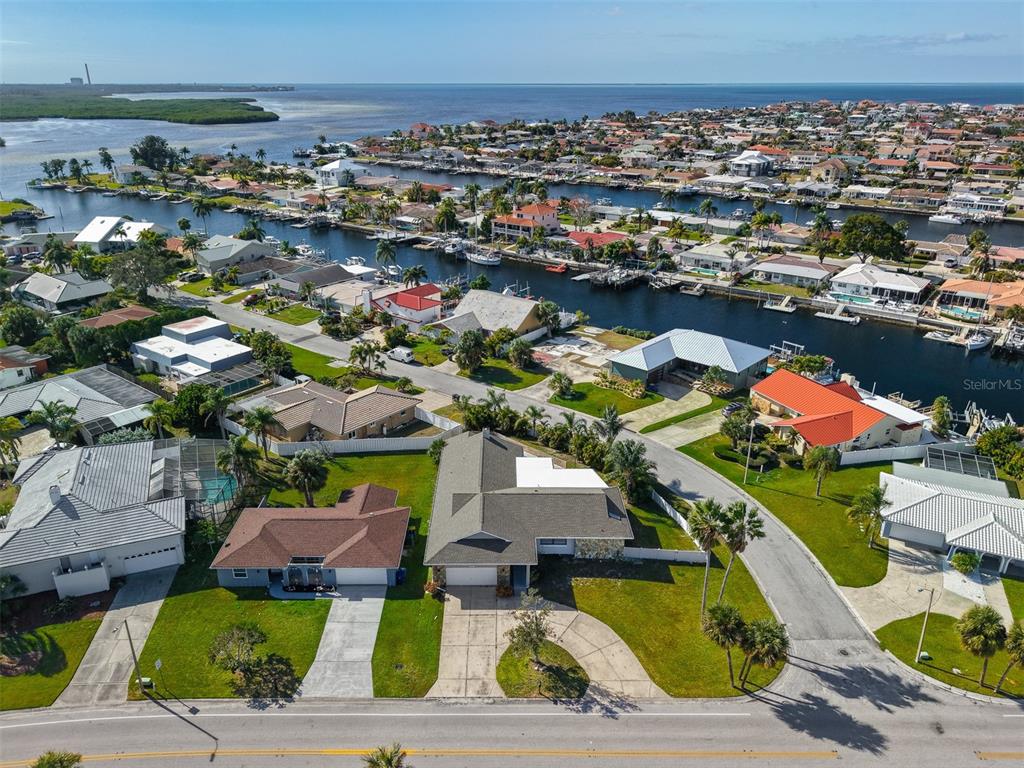 An aerial view shows a residential neighborhood with houses, canals, and boats near the water — 3848 TOPSAIL TRAIL, NEW PORT RICHEY, FL