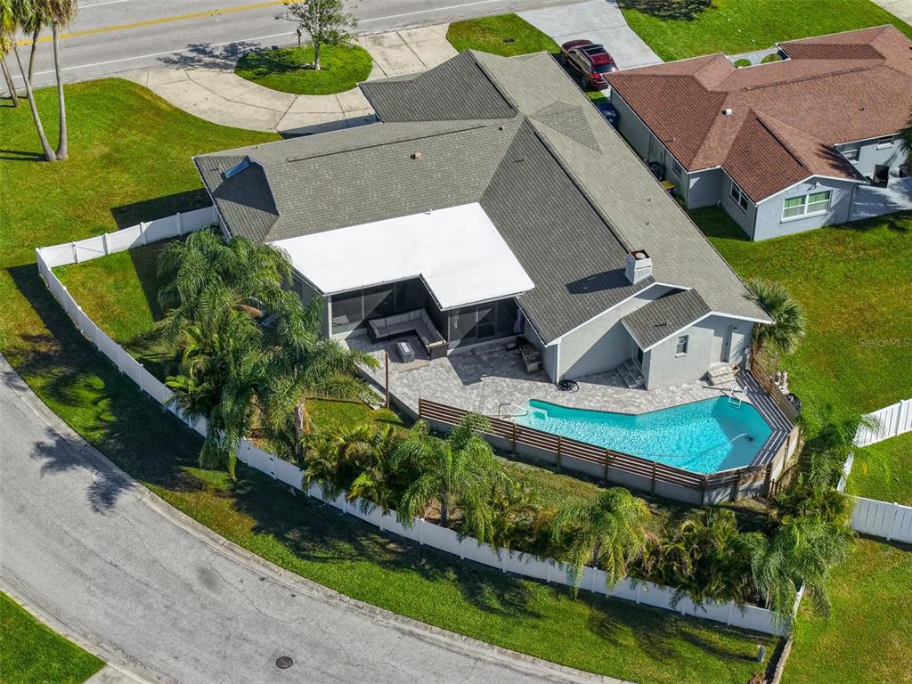 An aerial view shows a house with a gray roof, a pool, and a white fence — 3848 TOPSAIL TRAIL, NEW PORT RICHEY, FL