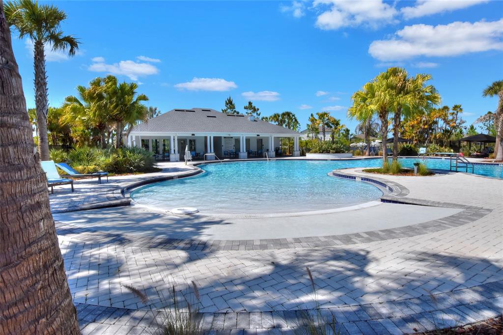 A swimming pool with a zero-entry edge sits in front of a community clubhouse — 3603 NATURAL TRACE, PLANT CITY, FL