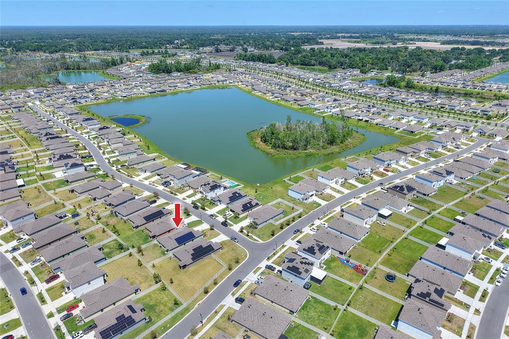 An aerial view shows a suburban neighborhood with a large central lake and houses — 3603 NATURAL TRACE, PLANT CITY, FL