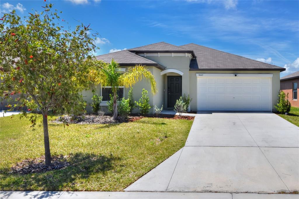 A single-story house with a beige stucco exterior, a gray roof, and a concrete driveway — 3603 NATURAL TRACE, PLANT CITY, FL