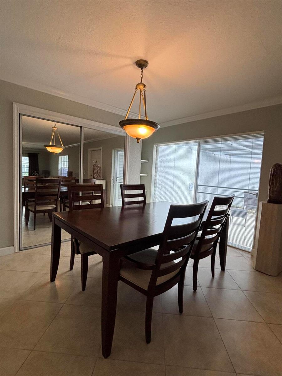 A dining room features a dark wood table, matching chairs, a pendant light, and mirrored doors — 10084 S 42nd Dr Drive # 122, Boynton Beach FL 33436, BOYNTON BEACH, FL