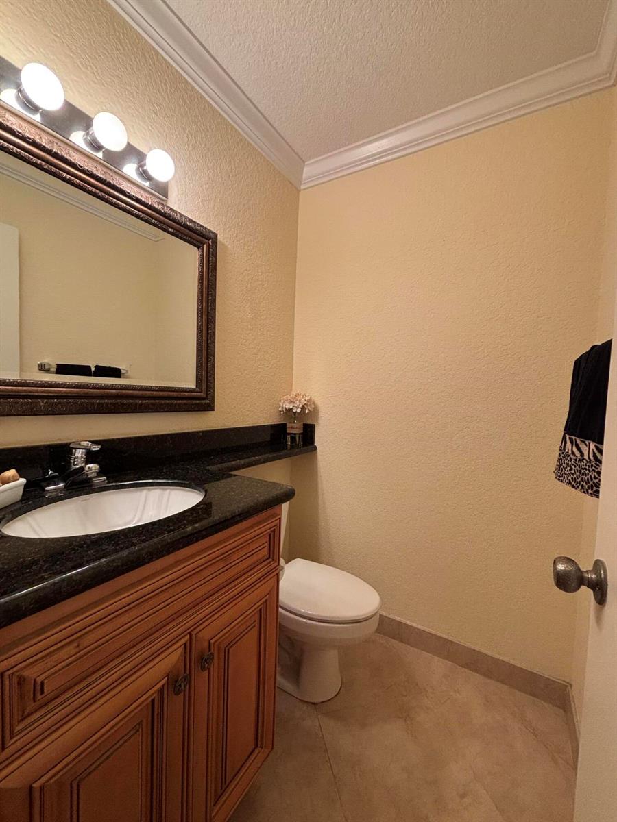 A bathroom features a wooden vanity with a black countertop, a mirror, and a toilet — 10084 S 42nd Dr Drive # 122, Boynton Beach FL 33436, BOYNTON BEACH, FL
