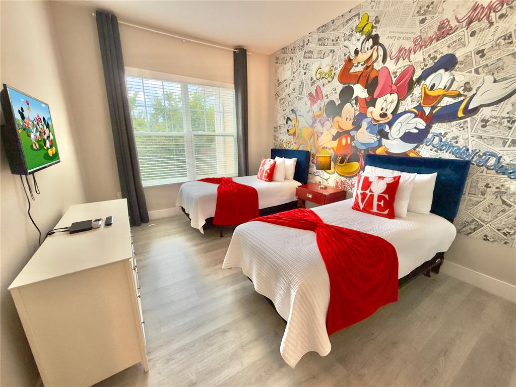 A bedroom features two twin beds, a Disney-themed mural, and a white dresser — 7498 SUNVILLE AVENUE, KISSIMMEE, FL