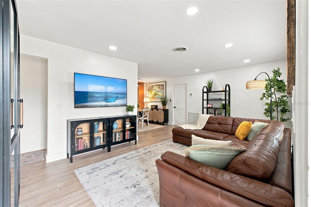 A living room features a brown leather sectional, a television, and a black media console — 2048 JEFFERSON AVENUE, DUNEDIN, FL