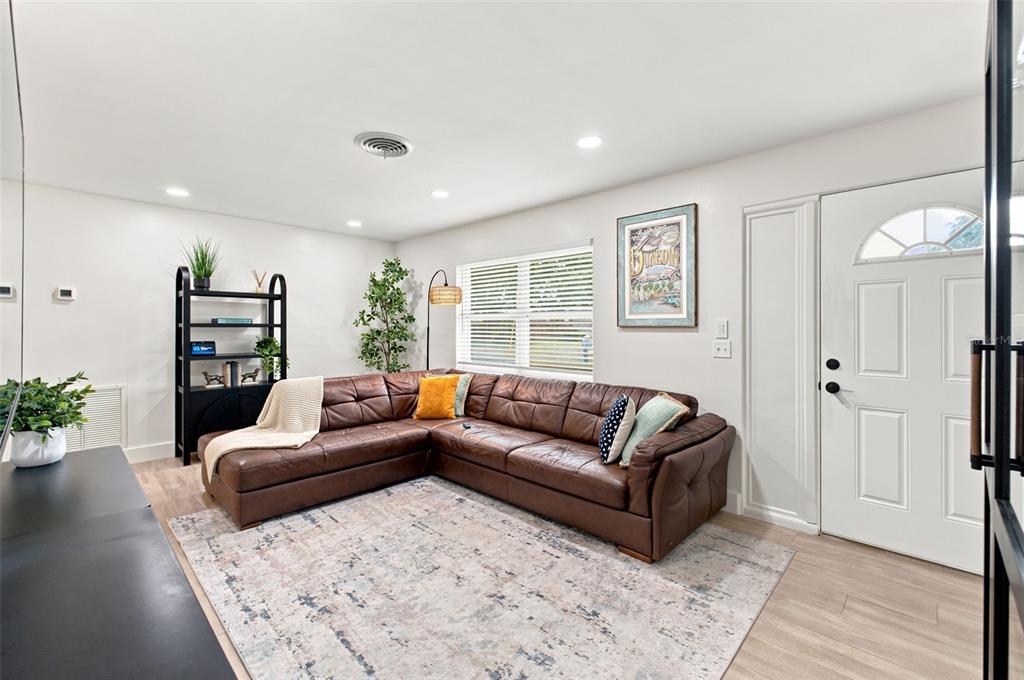 A living room features a brown leather sectional, a patterned area rug, and a white door — 2048 JEFFERSON AVENUE, DUNEDIN, FL