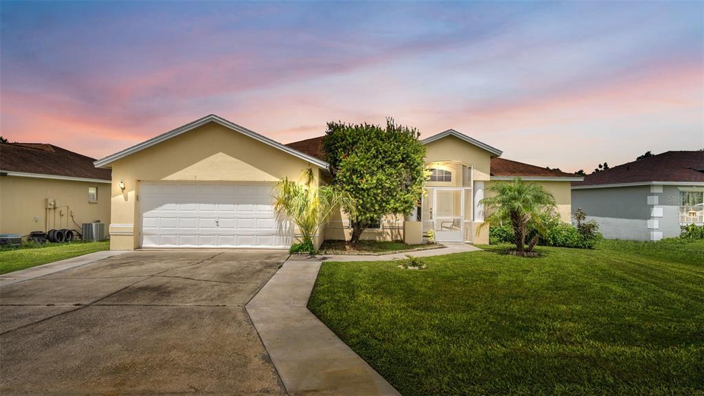 A single-story house with a yellow exterior, a two-car garage, and a front lawn — 3549 MANOR LOOP, LAKELAND, FL