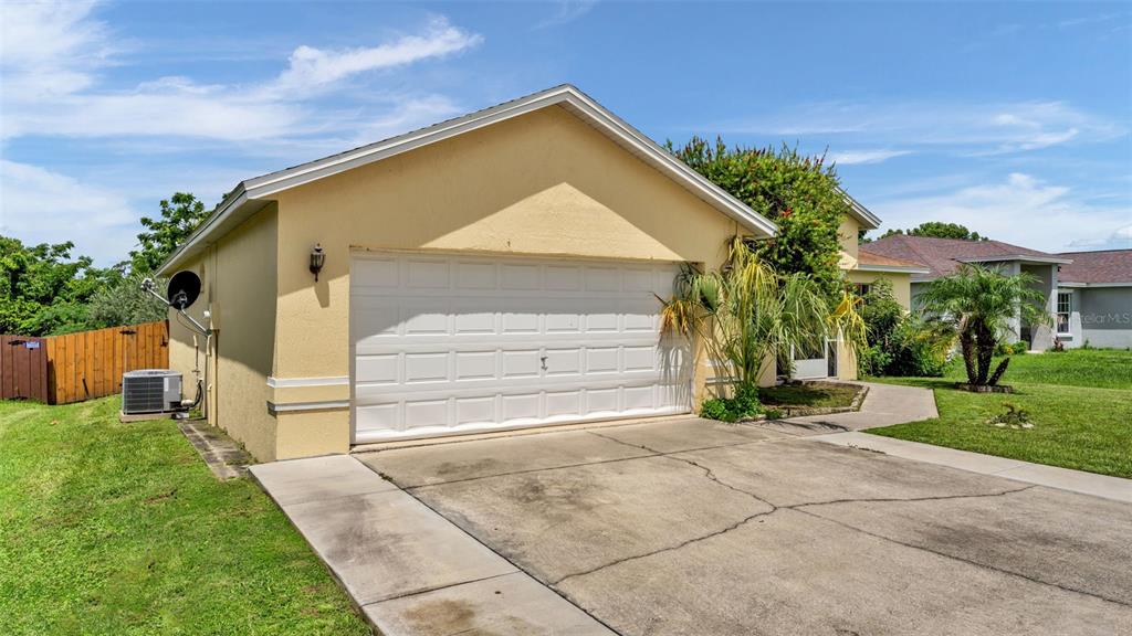 A yellow house with a two-car garage and a concrete driveway under a blue sky — 3549 MANOR LOOP, LAKELAND, FL