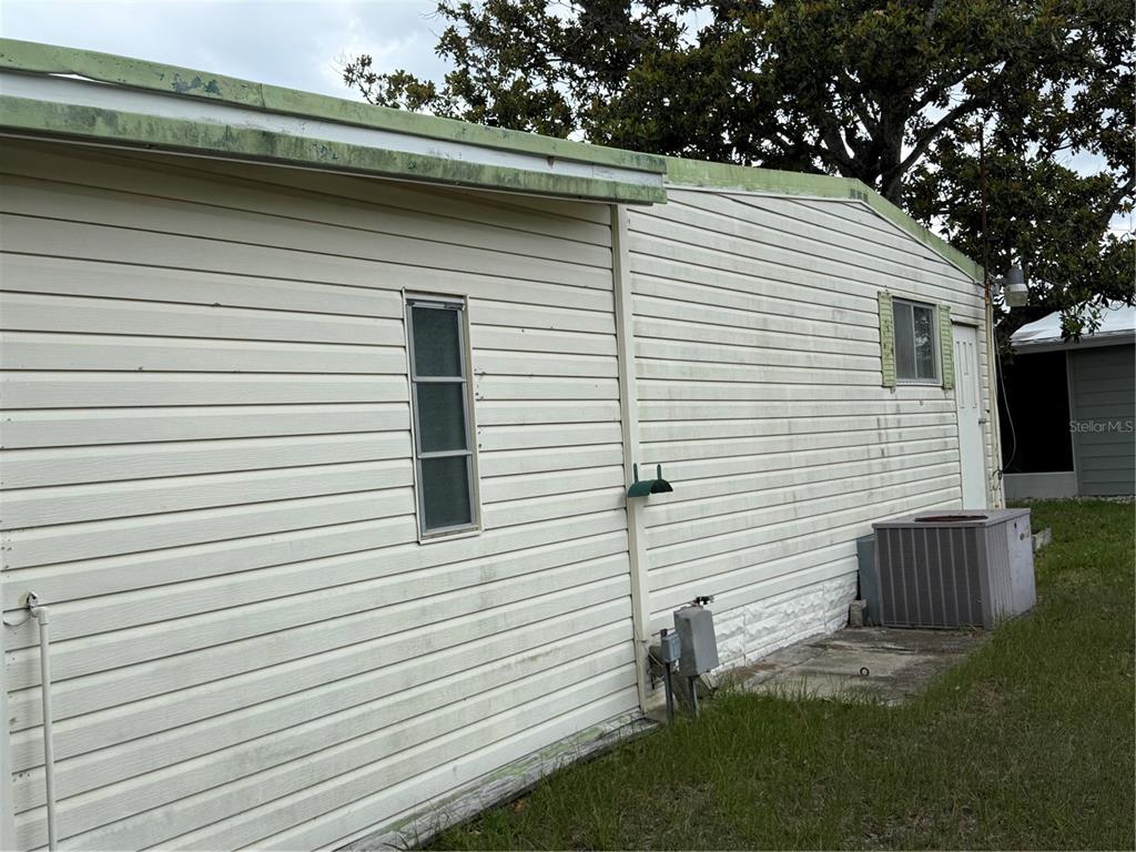 The exterior of a mobile home features light-colored horizontal siding, a window, and an AC unit — 12326 CONDE DRIVE, BROOKSVILLE, FL