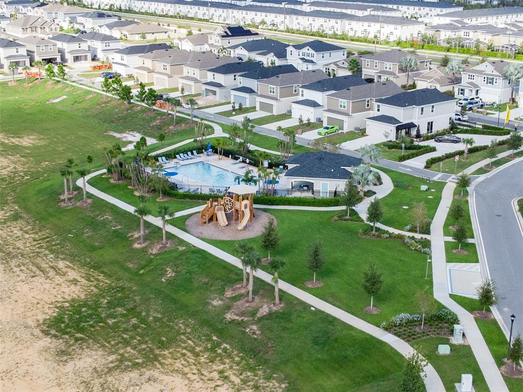 An aerial view shows a community swimming pool and playground surrounded by suburban houses — 757 STONEY POINT CIRCLE, DAVENPORT, FL