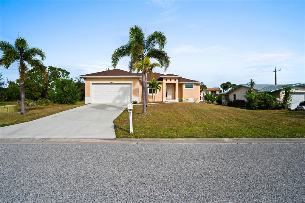 A single-story house with a beige exterior, a two-car garage, and palm trees — 241 ANNAPOLIS LANE, ROTONDA WEST, FL