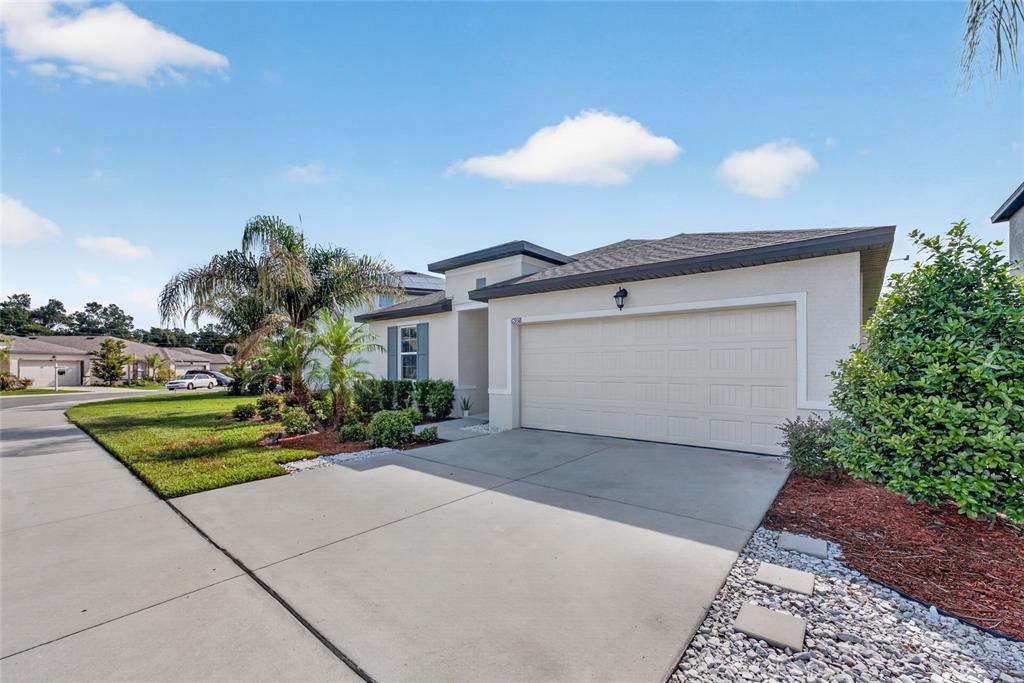 A single-story house with a two-car garage, a concrete driveway, and a landscaped front yard — 6938 SHELBY LYNN WAY, ZEPHYRHILLS, FL