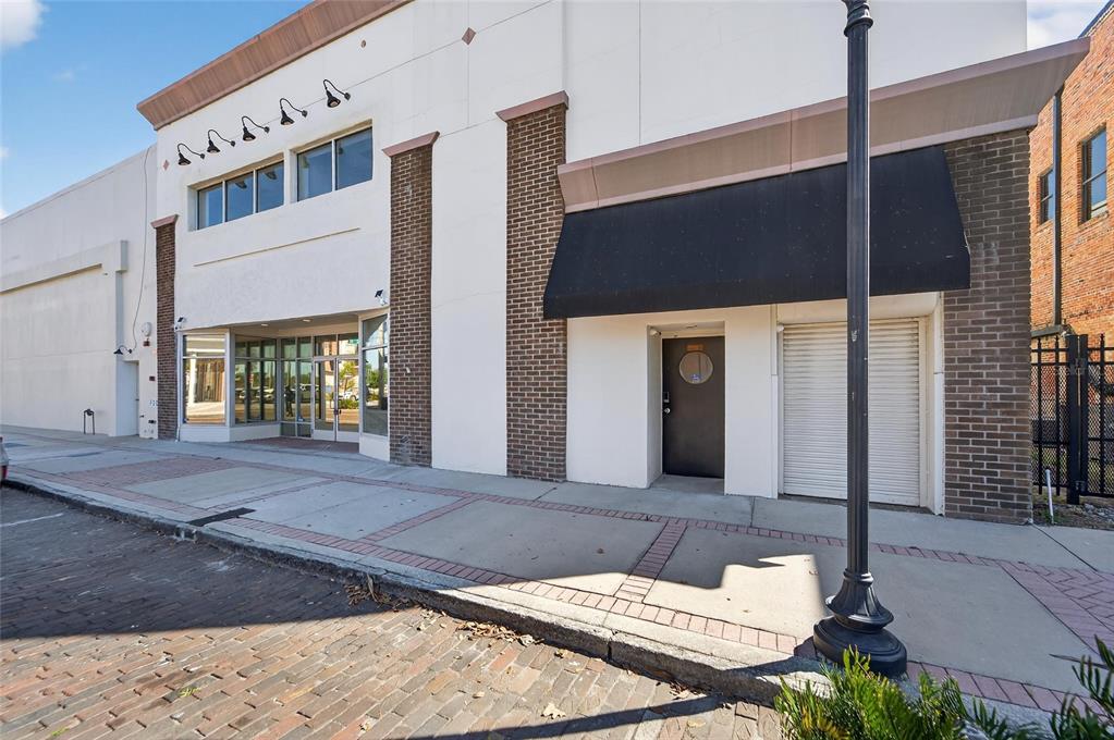 A street-level view of a commercial building exterior with brick accents and a black awning — 106 N EVERS STREET, PLANT CITY, FL