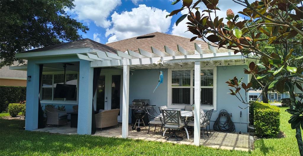 A light blue house features a covered patio with a wooden pergola and outdoor furniture — 11300 MOLLYMAWK COURT, NEW PORT RICHEY, FL