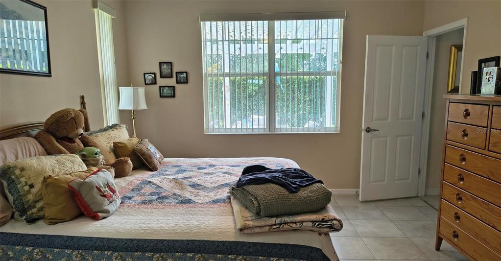 A bedroom features a bed with a patterned quilt, a wooden dresser, and a window — 11300 MOLLYMAWK COURT, NEW PORT RICHEY, FL