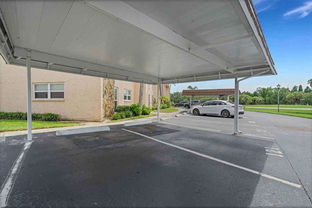An outdoor parking area features a covered carport with numbered spaces next to a building — 121 ASPEN CIRCLE UNIT 121, SEMINOLE, FL