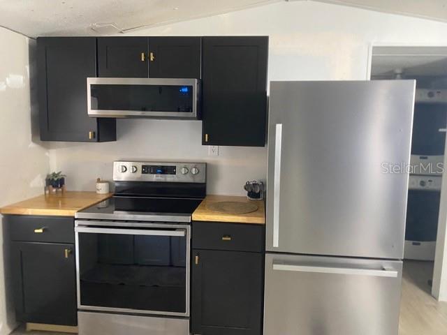 A kitchen features black cabinets, stainless steel appliances, and light wood countertops — 2789 MERIDITH LANE, PONCE DE LEON, FL