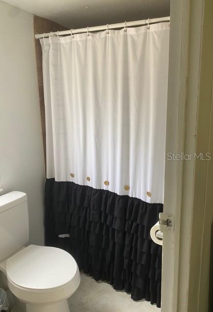 A bathroom features a white toilet and a white and black ruffled shower curtain — 2789 MERIDITH LANE, PONCE DE LEON, FL
