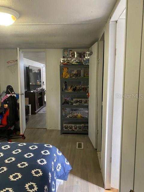 A bedroom features a patterned blue bedspread, a tall display cabinet, and a doorway — 2789 MERIDITH LANE, PONCE DE LEON, FL