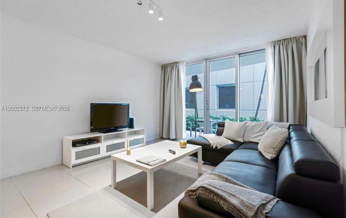 A living room features a black leather sectional sofa, a white coffee table, and a television console — 3901 S Ocean Dr # 1B, Hollywood FL 33019, HOLLYWOOD, FL