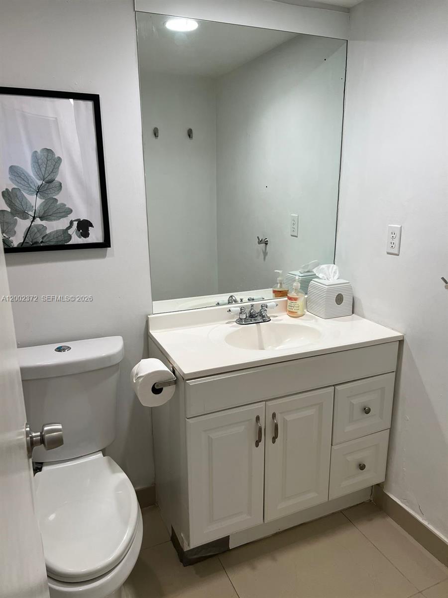 A bathroom features a white vanity with a sink, a toilet, and a wall mirror — 3901 S Ocean Dr # 1B, Hollywood FL 33019, HOLLYWOOD, FL
