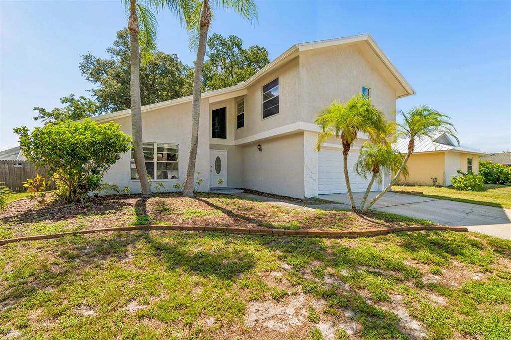 A two-story house with a white stucco exterior, a garage, and palm trees in front — 4163 MALLARD DRIVE, SAFETY HARBOR, FL