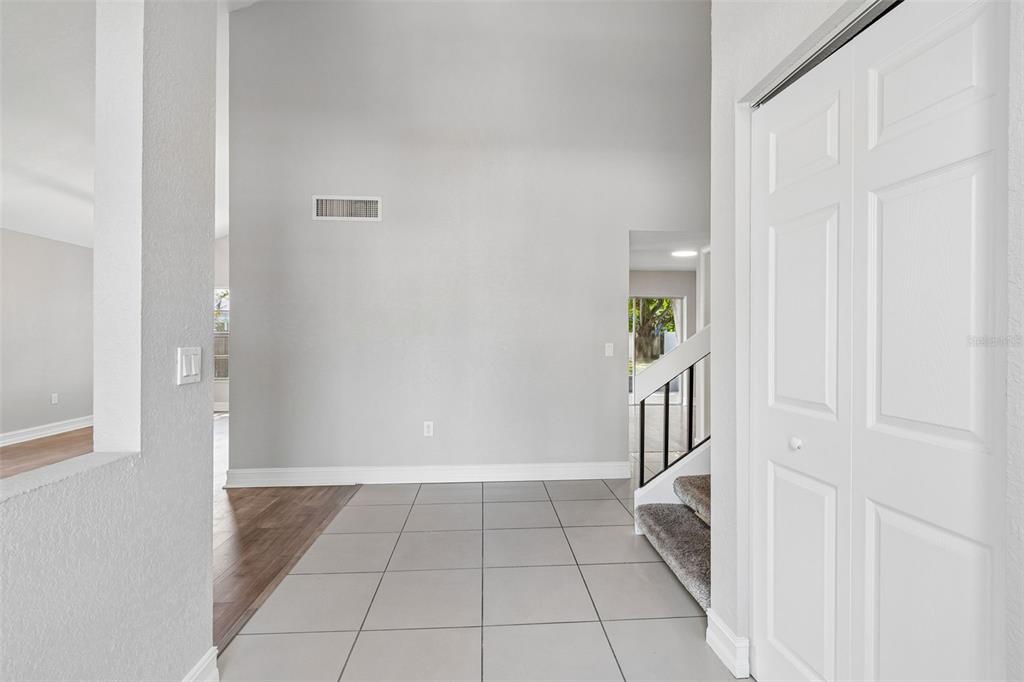 An entryway features gray tile flooring, a carpeted staircase, and a white closet door — 4163 MALLARD DRIVE, SAFETY HARBOR, FL