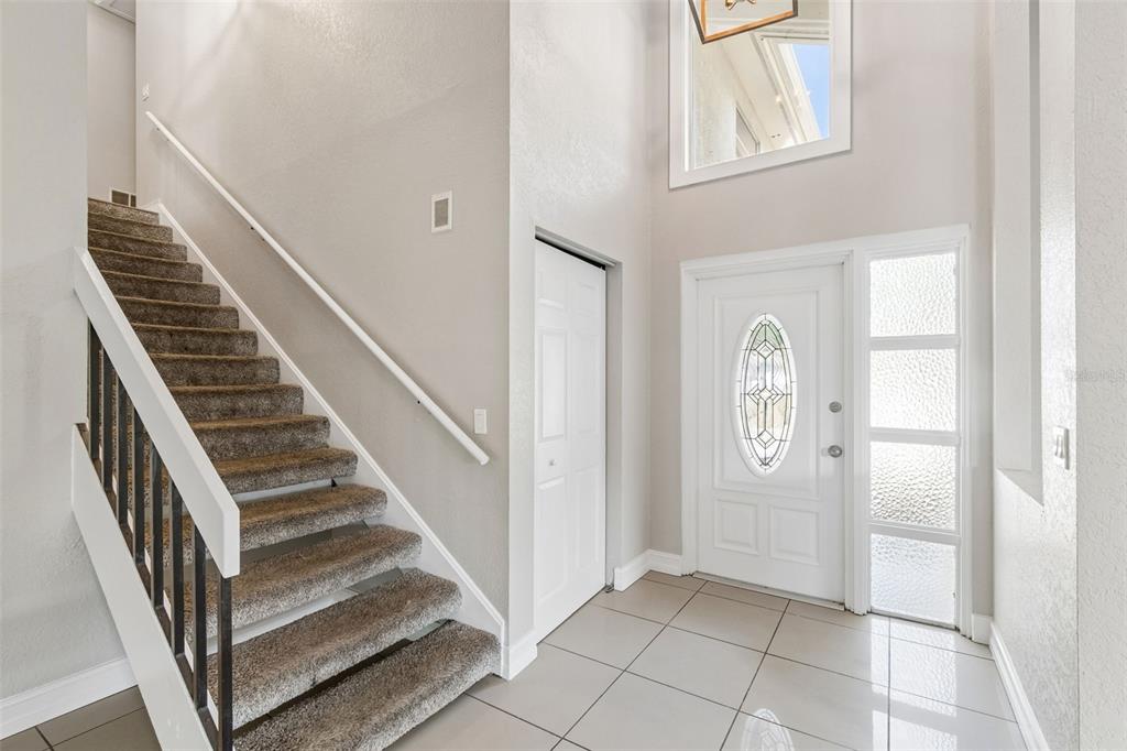 An entryway features a carpeted staircase, a white front door with glass, and tiled flooring — 4163 MALLARD DRIVE, SAFETY HARBOR, FL