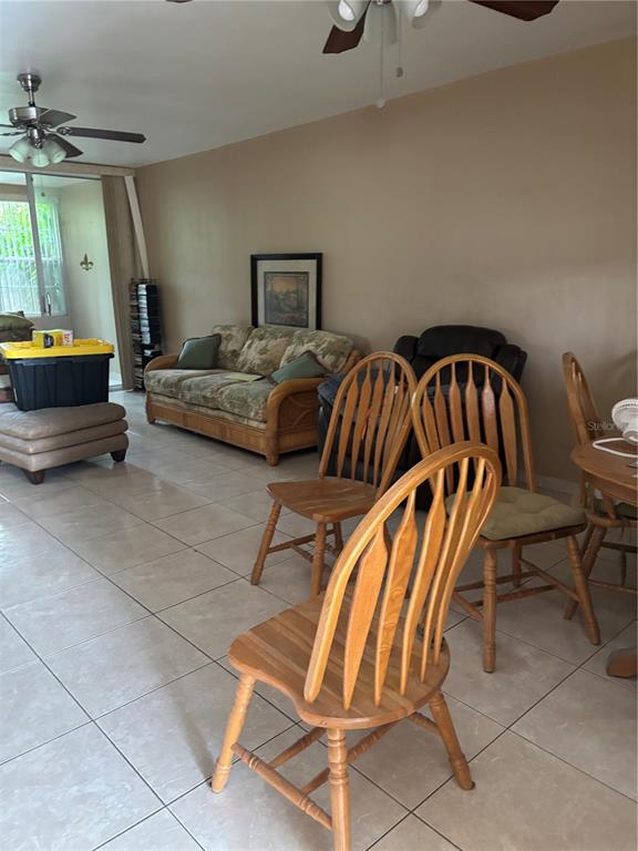 A dark wicker chair sits on a concrete patio surrounded by lush green foliage — 1433 S BELCHER ROAD UNIT G1, CLEARWATER, FL