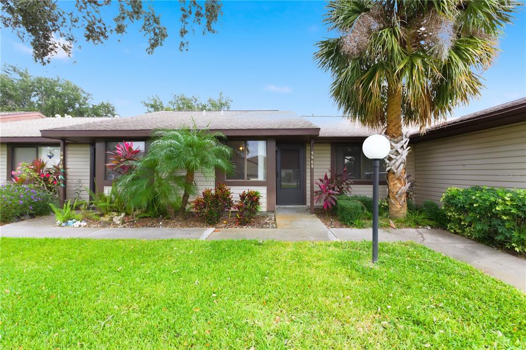 A screened-in porch with a ceiling fan overlooks a grassy backyard and neighboring houses — 5908 36TH AVENUE CIRCLE W, BRADENTON, FL