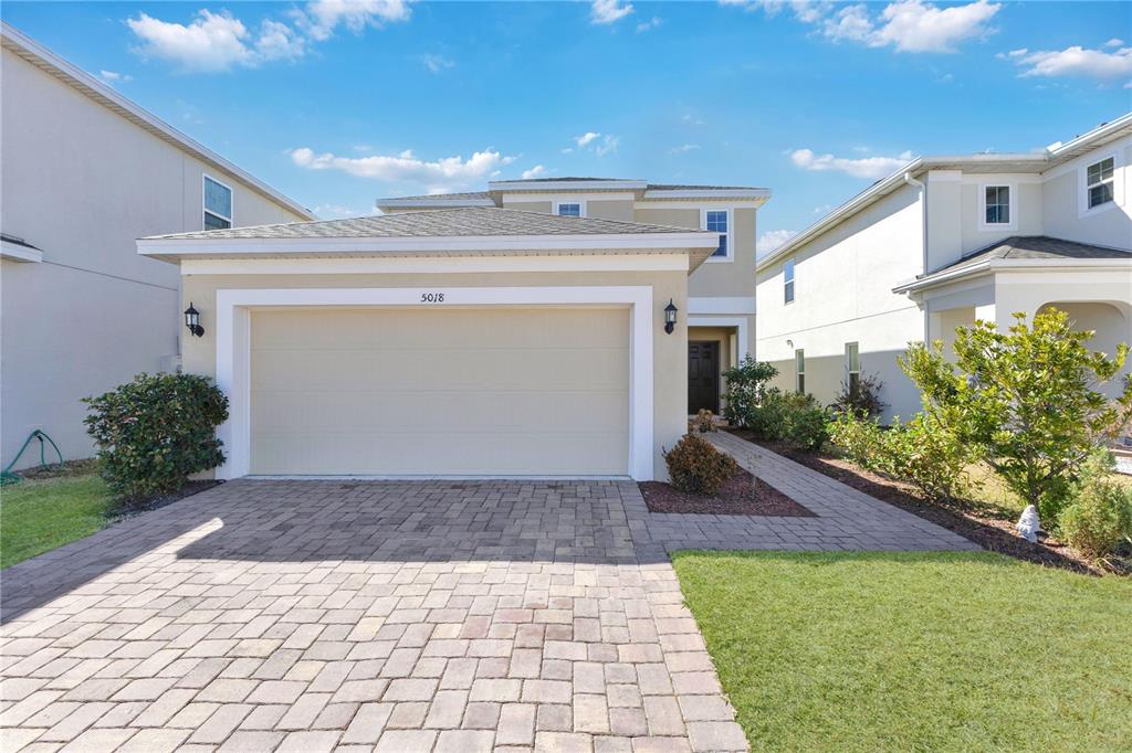 A two-story house features a beige exterior, a paved driveway, and a two-car garage — 5018 ROYAL POINT AVENUE, KISSIMMEE, FL