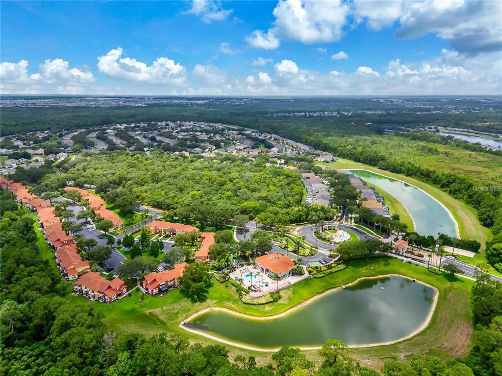 An aerial view shows a residential community with a clubhouse, swimming pool, and two ponds — 8411 CRYSTAL COVE LOOP, KISSIMMEE, FL