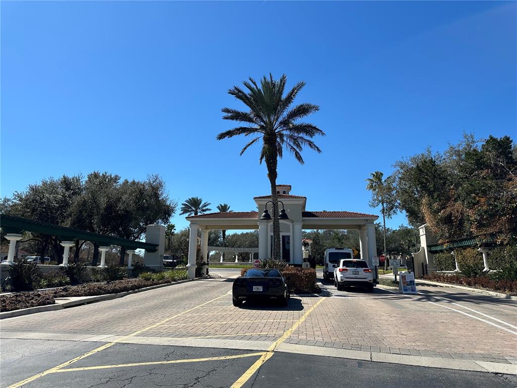 A gated community entrance features a palm tree, a guardhouse, and two vehicles — 8411 CRYSTAL COVE LOOP, KISSIMMEE, FL