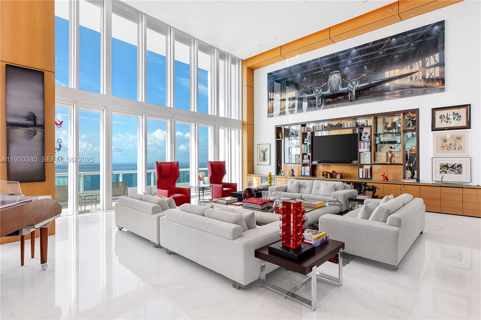 A spacious living room features floor-to-ceiling windows, white marble floors, and a large airplane mural — 1643 Brickell Ave, Miami FL 33129, MIAMI, FL