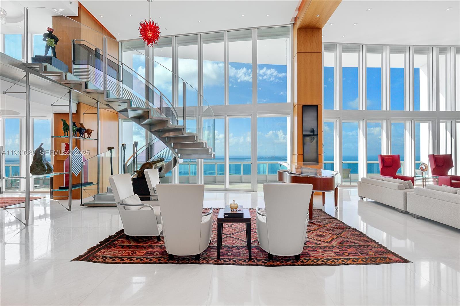 A modern living room features a spiral staircase, floor-to-ceiling windows, and ocean views — 1643 Brickell Ave, Miami FL 33129, MIAMI, FL