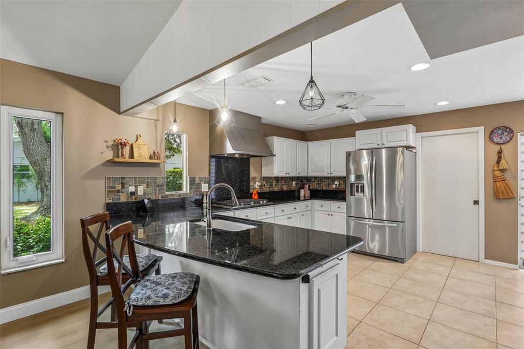 A kitchen with white cabinets, dark granite countertops, and a stainless steel range hood — 3757 COUNTRYSIDE ROAD, SARASOTA, FL