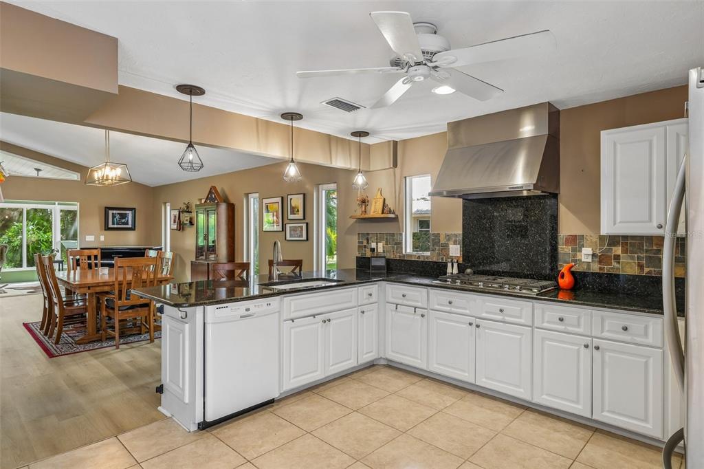 A kitchen with dark granite countertops, white cabinets, stainless steel appliances, and pendant lighting — 3757 COUNTRYSIDE ROAD, SARASOTA, FL