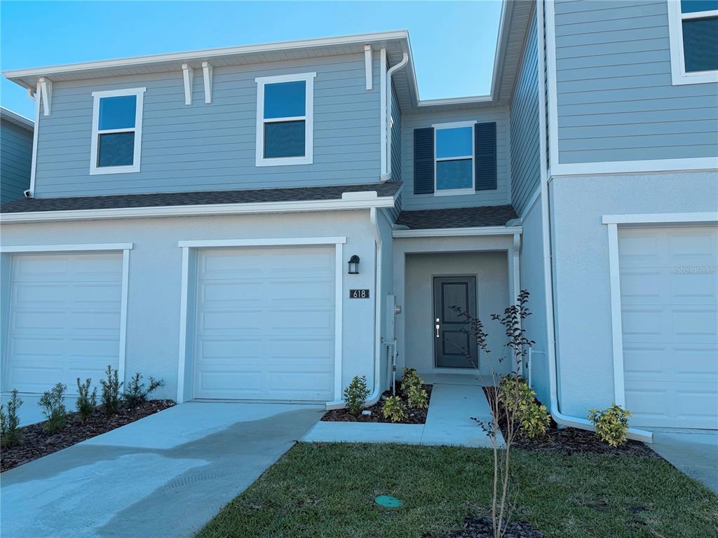 A two-story townhouse exterior features light blue siding, a garage, and a front entryway — 618 POPPY LANE, DUNDEE, FL