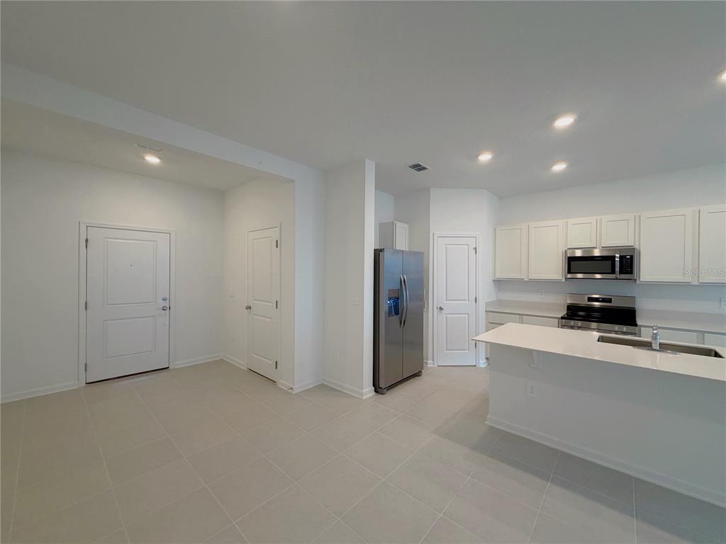 A kitchen with white cabinets, stainless steel appliances, and a peninsula island on tiled floors — 618 POPPY LANE, DUNDEE, FL
