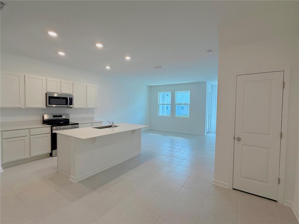 A modern kitchen features white cabinets, a central island, and tile flooring in an open space — 618 POPPY LANE, DUNDEE, FL